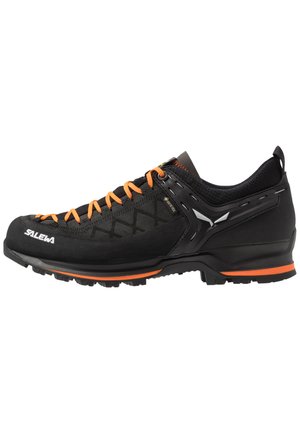 Black climbing shoes with orange laces and stitching. Features a textured upper, reinforced sides, and a rugged sole for traction.