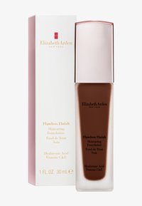 Fond de teint Flawless Finish dans un flacon en verre brun rectangulaire et haut avec un bouchon métallique rose doré et un emballage blanc comportant du texte doré.