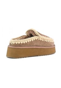 Pantofole in suede marrone con interni morbidi, dettagli in crochet crema e una robusta suola in gomma, caratterizzate da un design arrotondato e aperto all'estremità.