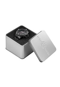 Zwarte horloge tentoongesteld in een zilveren blikken doos met een gestructureerde zwarte binnenkant. Het horloge heeft een genummerde bezel en gedurfde contrasterende wijzers.