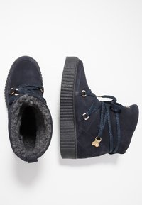 Námořnické semišové kotníkové boty s hrubou gumovou podrážkou, šedou fleecovou podšívkou a třpytivými tkaničkami. Obsahují akcenty z pozlaceného kovu.