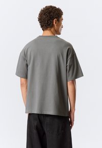 Γκρι βαμβακερό t-shirt με κοντά μανίκια, στρογγυλή λαιμόκοψη και άνετη εφαρμογή. Διαθέτει απαλό ύφασμα και μονόχρωμο σχέδιο χωρίς σχέδια.