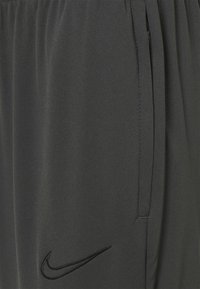 Donkergrijze sportshorts van lichtgewicht stof. Voorzien van een elastische tailleband, zijzakken en een gestikt zwart Nike-logo.