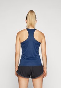 Marineblauw sport tanktop met een racertasontwerp, gemaakt van een gladde, rekbare stof. Gecombineerd met zwarte shorts met een gebogen zoom.