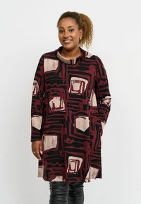 Pitkähihaisen maroonin ja mustan mekko abstrakteilla neliökuvioilla. Varustettu kaarrokkeella ja sivutaskuilla. Sileä kangas.