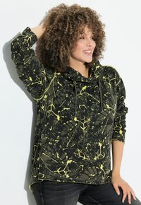 Sudadera con capucha en negro con un patrón abstracto amarillo, que presenta un corte holgado, cordones y mangas largas. Textura de tela suave.