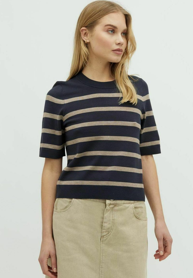 Marinblå randig kortärmad tröja med beige horisontella ränder, rund halsringning och ett texturerat stickat mönster, bärs med en beige kjol.
