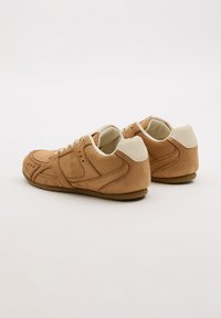 Zapatillas de gamuza marrón claro con detalles en blanco, puntera redondeada, diseño de cordones y costuras detalladas. Suela de goma para mayor tracción. Vista trasera mostrada.