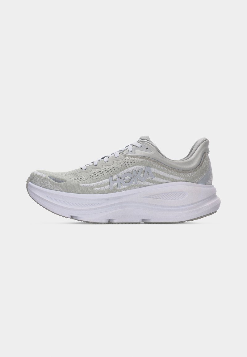 Hellgrauer HOKA-Laufschuh mit dickem weißem Sohlenabsatz, atmungsaktivem Mesh-Obermaterial und Schnürdesign, von der Seite auf einem schlichten Hintergrund gezeigt.