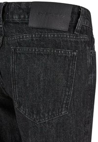 Vaqueros de mezclilla negra con una textura suave, diseño clásico de cinco bolsillos y una etiqueta de cuero en la cinturilla grabada con "FY STUDIOS."