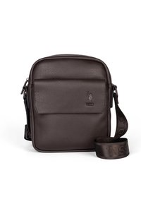 Hnědá kožená kabelka přes rameno s texturovaným povrchem, horním zipem, přední kapsou a nastavitelným popruhem s logem. Rozměry přibližně 10x8 palců.