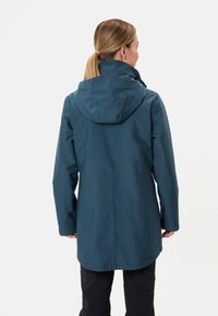 Giacca impermeabile color teal con cappuccio, caratterizzata da un taglio dritto e maniche lunghe. Tessuto liscio, design semplice e senza motivi visibili.