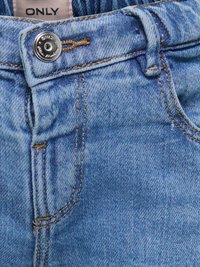 Ceinture d'un jean en denim bleu clair avec un bouton en métal et une étiquette de marque visible "ONLY" au-dessus du boutonnière.
