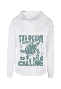 Felpa bianca con cappuccio e grafica di una tartaruga circondata da onde oceaniche e il testo "L'OCENo chiama" in teal. Design morbido e casual.