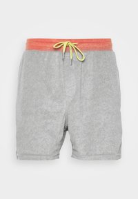 Pantalones cortos grises con una superficie texturizada, que presentan una cinturilla naranja y un cordón amarillo. Con aberturas de pierna cortadas y sin bolsillos.