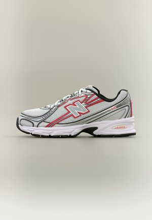 Bielo-šedý bežecký topánka s červenými a čiernymi akcentmi, sieťovaný zvršok, šnurovací dizajn a polstrovaná podrážka, zobrazený na neutrálnom pozadí.