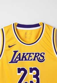 Žlutý basketbalový dres Los Angeles Lakers s číslem 23, fialovými a bílými detaily, logy Nike a NBA na přední straně.