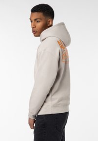 Light gray hooded sweatshirt made of soft fabric, featuring orange text design on the back, and ribbed cuffs and hem.