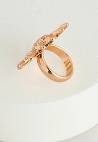 Roséguld ring med en bred, tekstureret top og en glat ring. Har et afrundet design med en poleret finish.