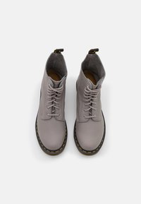 Stivali alla caviglia in pelle grigia con punta rotonda, design con lacci, colletto imbottito, cuciture gialle, suola nera e una piccola linguetta sul retro.