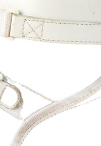 Gros plan de sangles blanches en cuir et tissu avec des détails de couture et une boucle, montrant l'usure et la texture sur un fond uni.