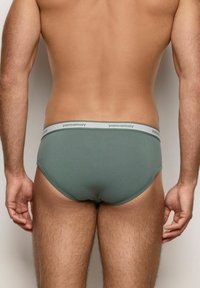 Grüne Brief-Unterwäsche im Stil mit einer weichen Textur, elastischem Bund mit "yamamay"-Logo und einem glatten, konturierten Design.