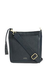 Sac bandoulière en cuir marine avec une surface texturée, une longue bandoulière ajustable, des finitions dorées et un pompon décoratif.