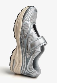 Shoe sportiv argintiu cu superior din plasă, guler căptușit și curea ajustabilă. Design texturat, talpă gri deschis și crampoane negre.