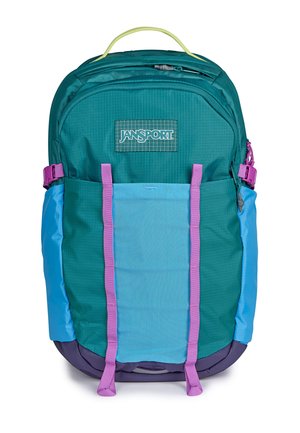 Sac à dos Jansport bleu sarcelle et bleu avec des bretelles violettes, une poignée supérieure, une poche avant zippée et des boucles de compression latérales sur fond blanc.