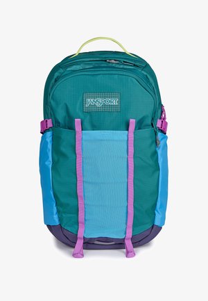 Türkis-blauer Jansport-Rucksack mit lila Trägern, oberem Griff, Front-Reißverschlusstasche und seitlichen Kompressionsschnallen auf weißem Hintergrund.