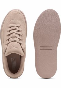 Bež nubukist spordijalatsid, millel on nööriga disain, pehmendatud keel ja tekstureeritud kummist tallad. Ülalt ja sisetaldalt on Puma logo.