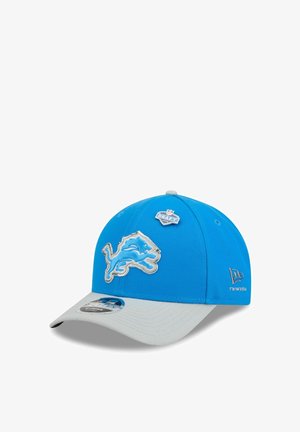 Blue and gray NFL Detroit Lions cap with team logo, NFL Draft 2023 pin, and New Era branding on side and brim sticker.