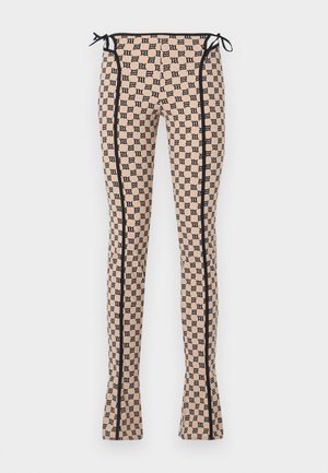 Kujundusega retuusid heledas virsiku toonis musta logo prindiga, mustade külgõmbluste ja paeltega vöökohta. Laienev disain.