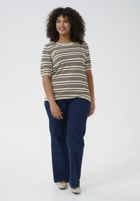 Top de rayas beige y negro de manga corta combinado con unos vaqueros acampanados azul oscuro. El conjunto tiene un ajuste holgado y una textura suave.
