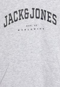 Szara tkanina z czarnym napisem „JACK & JONES” dużymi literami i mniejszym napisem „EST. 90 WORLDWIDE” poniżej.