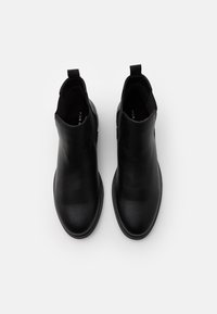 Bottines en cuir noir avec une finition lisse, tirette à l'arrière et design à bout arrondi. Aucune décoration ni motif visible.