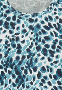 Korte mouwen top van zachte stof met een blauw en zwart abstract luipaardpatroon op een witte achtergrond. Ronde halslijn.