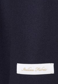 Tessuto blu scuro con una consistenza morbida, caratterizzato da un'etichetta bianca con la scritta "Tessuto Italiano" in elegante corsivo dorato.