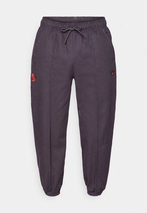 Grijze sportieve joggingbroek met elastische tailleband, trekkoord en taps toelopende boorden. Heeft een rood logo borduursel op één dij.
