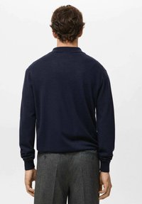 Granatowy, długi rękaw koszulki polo z prążkowanym kołnierzykiem i mankietami, zaprojektowany w dopasowanym kroju, pokazany od tyłu. Teksturowana tkanina podkreśla komfort.