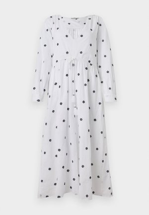 Witte jurk met lange mouwen en een V-hals. Bevat zwarte bloemenborduursels en een trekkoord in de taille met franje. Zacht, lichtgewicht stof.