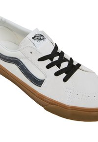 Hvide suede sneakers med sorte snørebånd og side-stribe. Har en gummirubber sål, polstret krave og Vans-logo på tungen.