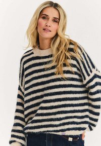 Sweter w paski o miękkiej, puszystej teksturze; posiada naprzemienne poziome paski w kolorze granatowym i kremowym, zaokrąglony dekolt oraz luźny krój.