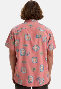 Korte mouwen shirt van lichtroze stof met kleurrijke, abstracte gezichten en palmbladpatronen. Het heeft een knoopsluiting bij de kraag en een ontspannen pasvorm.