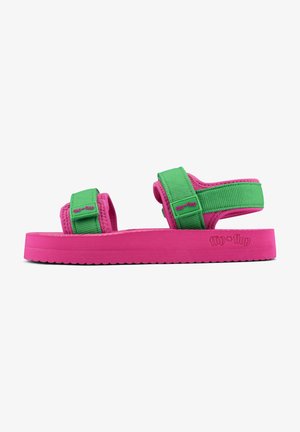 Pink sandals with green adjustable straps, featuring a textured sole and branded side detail. Soft material and flat design.