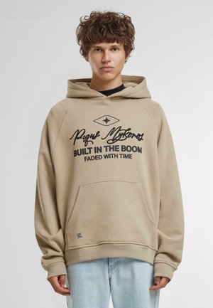 Hoodie beige avec une poche avant, texte graphique noir et logo en forme de diamant. Texture douce avec un ourlet et des poignets côtelés. Coupe décontractée.