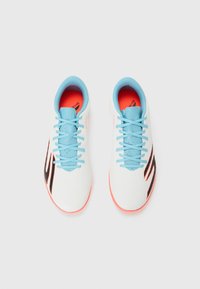 White athletic shoes with a textured surface, blue laces, and bright orange soles, featuring a black accent design on the sides.