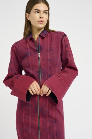Red denim jacket with a zip closure, long flared sleeves, and vertical seam detailing. Features a collar and an even texture.