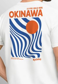 Weißes Baumwoll-T-Shirt mit einem retro Grafikdesign, das wellenförmige blaue Linien und eine orangefarbene Sonne zeigt. Der Text beinhaltet "OKINAWA" und "Kyūshū."