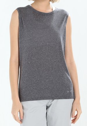 Haut de sport sans manches gris foncé porté par une personne avec un pantalon gris clair, montré du cou aux hanches sur un fond uni.